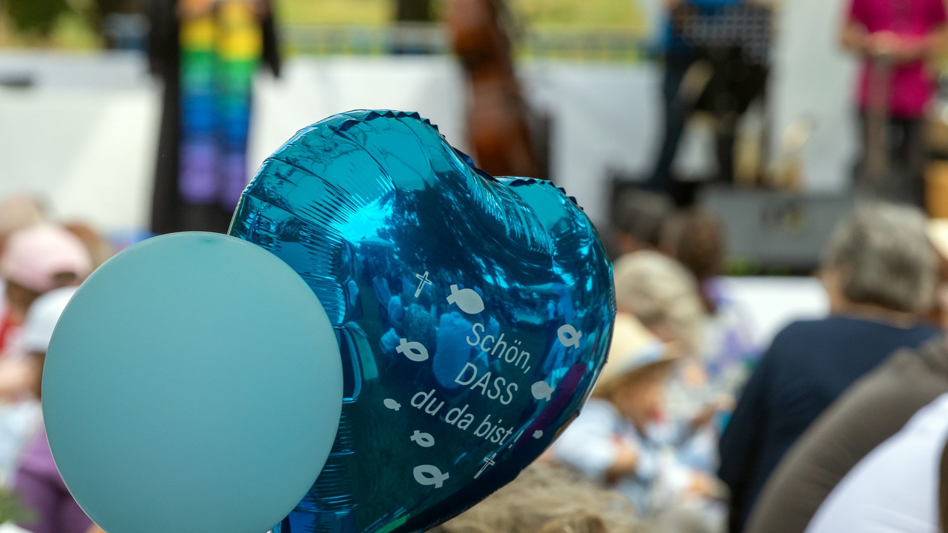 Zwei Luftballons beim "Main Tauffest 2022". Einer ist herzförmig und trägt die Aufschrift "Schön, dass du da bist".